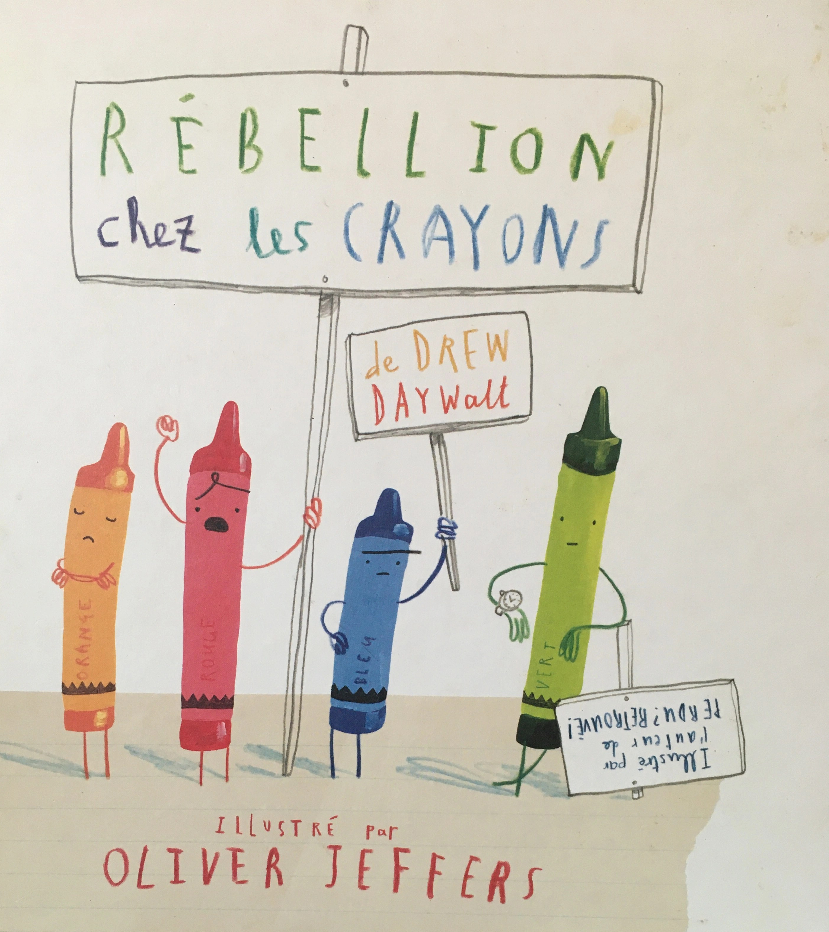 On voit des crayons brandir des panneaux de manifestations